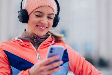 Young woman taking a break from running in the city and using smartphone