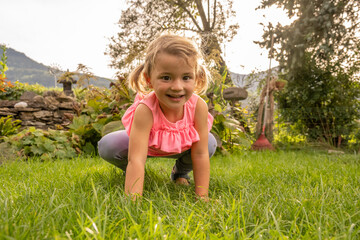 Little blond girl in backyard with pink shirt smiling into the camera