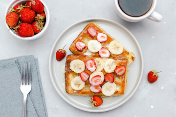 Square belgian waffles with strawberries berries,bananas,condensed milk,honey on plate, cup of coffee espresso. Tasty breakfast, sweet dessert food.selective focus, close up top view flat lay