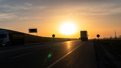 View of trucks carrying loads at sunrise