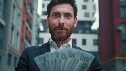Rich successful businessman hold income salary dollars in hands boast wealthy win cash prize lot of banknotes enjoy profitable business deal satisfied owner look at camera suggest financial exchange
