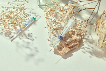 Medicine concept mockup with syringe on a delicate natural beige background and props. Health care,...