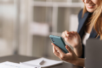 Young pretty asian stock manager checking list of product and working at workstation, texting mobile.