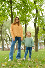 Fototapeta premium Loving mother walks with her cute daughter in the park. Mom and daughter pose holding hands in the park. loving family