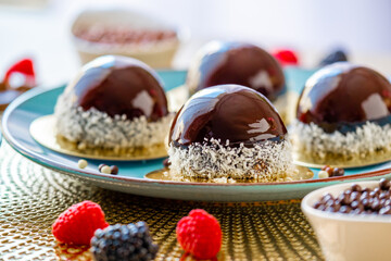 Chocolate round cake with raspberry set on a blue plate and chocolate decor on a beige table on a light background.Berry dessert.Delicate airy cake souffle.Appetizing pastries.
