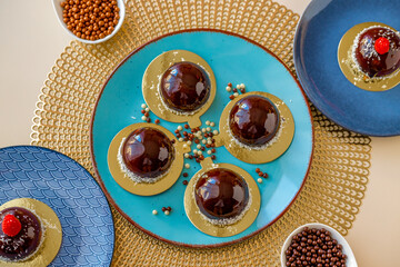 Chocolate round cake with raspberry set on a blue plate and chocolate decor on a beige table on a light background.Berry dessert. airy cake souffle.Appetizing cupcakes and pastries.