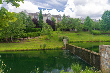 landscape design in a residential area with a pond, a dam and beautiful lawns.