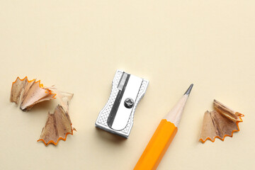 Pencil, sharpener and shavings on beige background, flat lay. Space for text