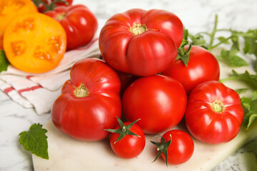 Pile of different ripe tomatoes on white table