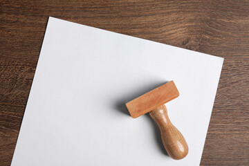 Blank sheet of paper and visa stamp on wooden table, top view