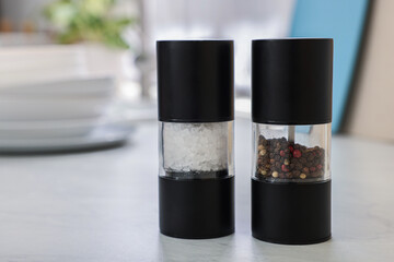 Salt and pepper shakers on white table, space for text