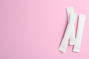 White sticks of sugar on pink background, flat lay. Space for text