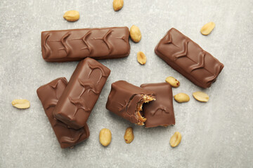 Chocolate bars with caramel, nuts and nougat on light grey table, flat lay
