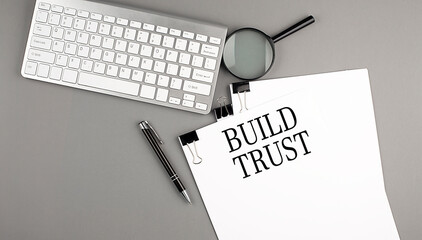 BUILD TRUST text on paper with keyboard, magnifier and pen. Business concept