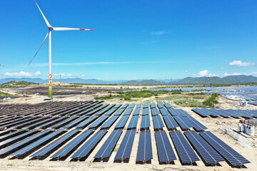 Solar panels and wind turbines generating alternative power and green renewable energy with blue sky background. Clean energy concept. Sustainable growth and climate change prevention.