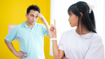 Irritated Asian American couple quarrelling at home, standing  together home, angry woman blaming, negative emotionally shouting at woman making excuses, points her finger, break up, problem
