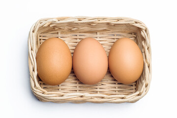 three chicken eggs in a rattan basket on white background