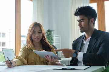 Successful business partner using digital tablet and discussing business strategy at office.