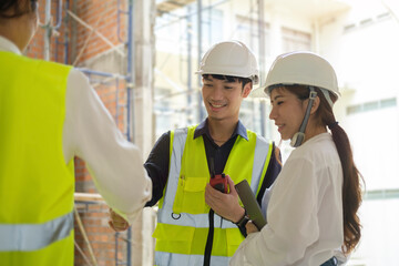 Engineers in yellow vests shaking hands while working at construction site. Building construction collaboration concept.