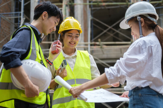 Architects wearing safety helmet discussing, planing, measuring layout at construction site.