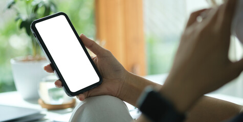Over shoulder view of woman hands holding mobile phone. Empty screen for your advertise text.