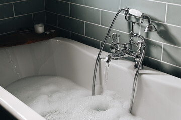 Hot bath. Warm water is drawn into the bath. Bathing with candles in a muted light. The concept of...