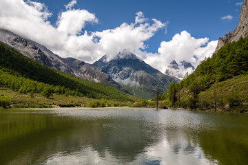 Naklejka na ściany i meble The mountain covered by cloud and a calm river in Daocheng Yading, Sichuan, China, horizontal image with copy space for text