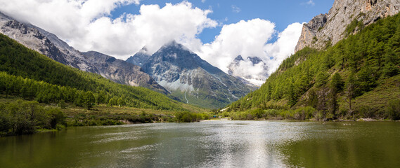 Panorama of the The green meadows, river and snow mountains in Yading and Daocheng, the last Shangri-La, in Sichuan, China, shot in summer time.