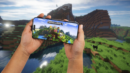 Fototapeta premium Child holding a smartphone iPhone 14 Pro with Minecraft mobile game app on the screen. Website blurred on background. Rio de Janeiro, RJ, Brazil. September 2022