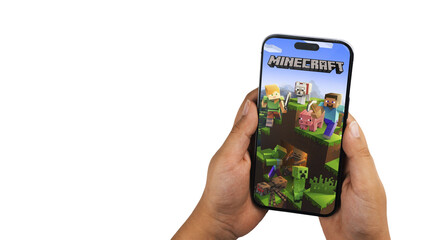 Fototapeta premium Child holding a smartphone iPhone 14 Pro with Minecraft mobile game app on the screen. White background. Rio de Janeiro, RJ, Brazil. September 2022