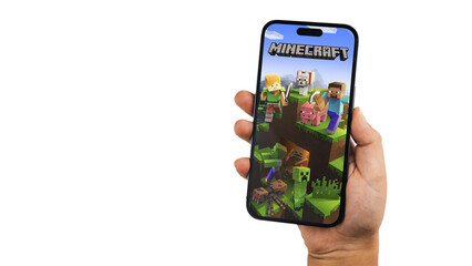 Fototapeta premium Child holding a smartphone iPhone 14 Pro with Minecraft mobile game app on the screen. White background. Rio de Janeiro, RJ, Brazil. September 2022
