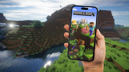 Obraz premium Child holding a smartphone iPhone 14 Pro with Minecraft mobile game app on the screen. Website blurred on background. Rio de Janeiro, RJ, Brazil. September 2022