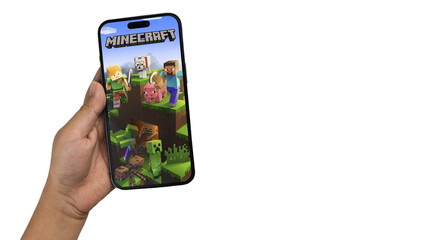 Fototapeta premium Child holding a smartphone iPhone 14 Pro with Minecraft mobile game app on the screen. White background. Rio de Janeiro, RJ, Brazil. September 2022