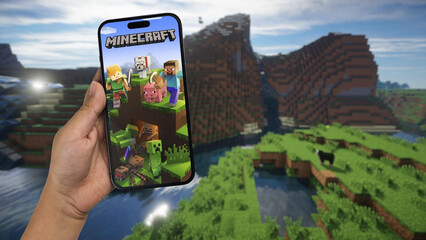 Fototapeta premium Child holding a smartphone iPhone 14 Pro with Minecraft mobile game app on the screen. Website blurred on background. Rio de Janeiro, RJ, Brazil. September 2022