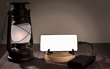 Smartphone with copy space, over wood and oil lamp, social problem energy poverty. background grey...