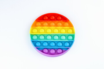 Rainbow colored round pop it toy on white background