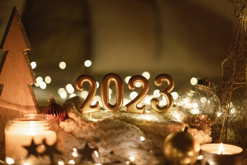 Happy New Year 2023. Number 2023 made by candles on a festive sparkling bokeh background in the...