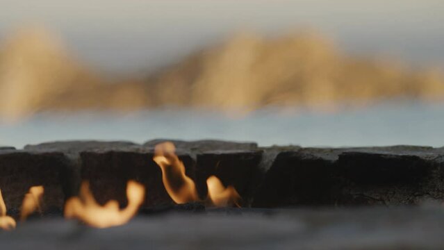 Close up fire pit with blurred background of infinity pool and Cabo mountain at sunset