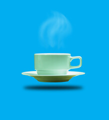 A hot cup of coffee and a saucer of fragrant smoke below. Black shadow separates from a coffee cup. and embed Clipping path. elegant blue background Copy area. vertical picture and side view