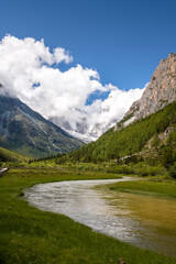 Fototapeta na wymiar S-shape river and mountains covered with clouds. The scenic spot is located in Daocheng Yading, Sichuan, China. Vertical image with copy space for text