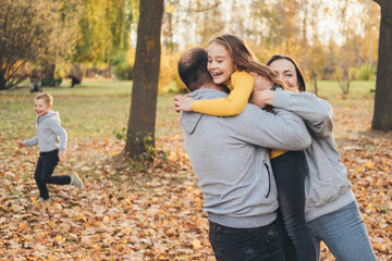 Happy family with little son and daughter spending time together in autumn park, enjoying a walk in nature. Happy family outdoors. Happy family, childhood