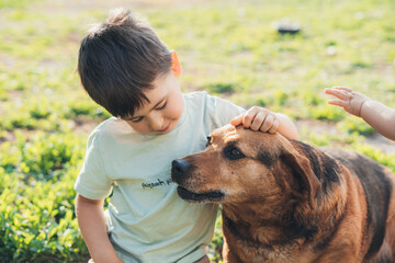 Happy kid and pet dog playing in rural areas in summer. Taking care of pets. Portrait of a child and an animal. Summer outdoor. Best friends.