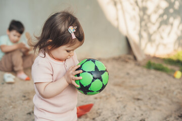 Baby girl standing in the garden with a soccer ball for children. Healthy activity. Summer outdoor fun activity. Healthy active lifestyle. Little garden.
