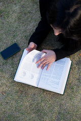 close-up of young woman lying on the lawn reading a book. Concept of hobbies, lifestyle and learning.