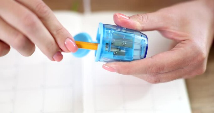 Woman hands are sharpening pencil with sharpener closeup