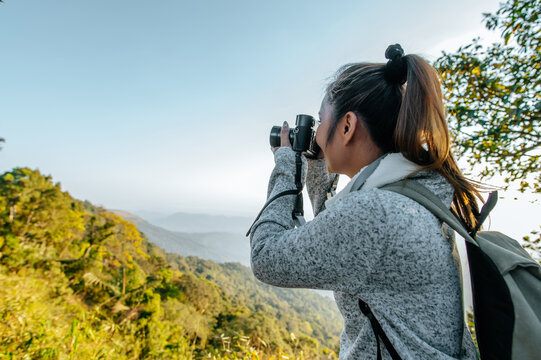 Young backpacker female use camera to take pictures in forest.