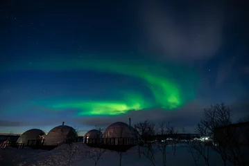 Selbstklebende Fototapeten Northern Lights also known as aurora, borealis or polar lights at cold night over igloo village. Beautiful night photo of magic nature of winter landscape © Michael Cola