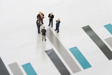 Investment consultant or advisor concept, miniature professional businessmen standing and looking, review on graph data report, background as partnership and investment concept.