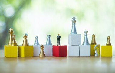 Miniature businessman standing on a wooden block with many of golden and silver color chess. Concept of business analysis and strategy. Stepping into the startup, new business player