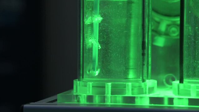 Hydrogen gas bubbles in tubes with water in a electrolyzer demonstrator, green light, slow motion